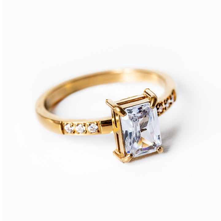 A gold-plated stainless steel ring with a yellow gold finish, featuring a clear, well-positioned cubic zirconia gemstone centerpiece.