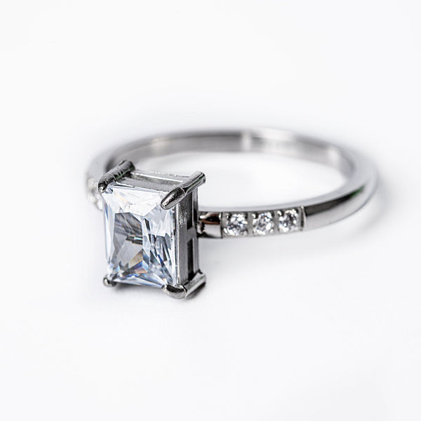 A silver-colored stainless steel ring with a gold plated band and a large central cubic zirconia gemstone surrounded by smaller clear crystals.