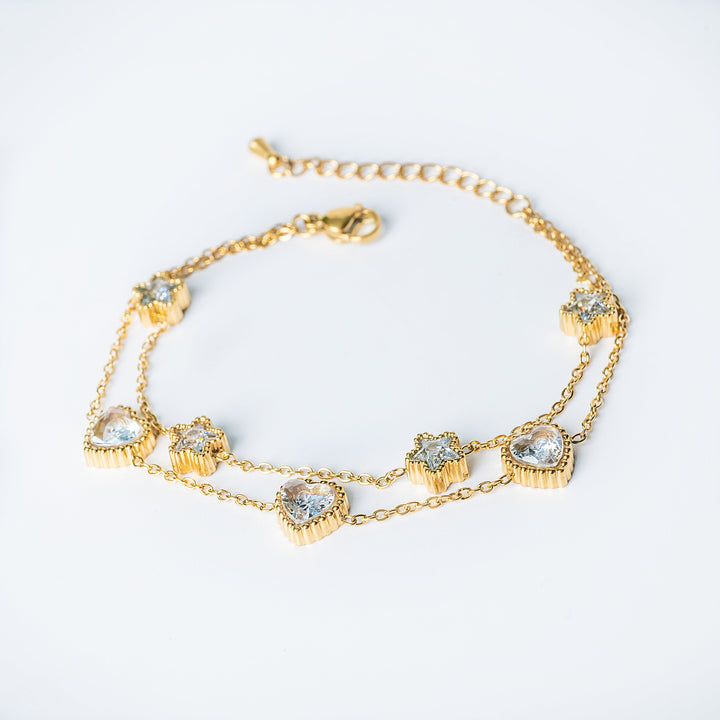 Gold Stacey bracelet with heart and star crystal charms displayed on a white background