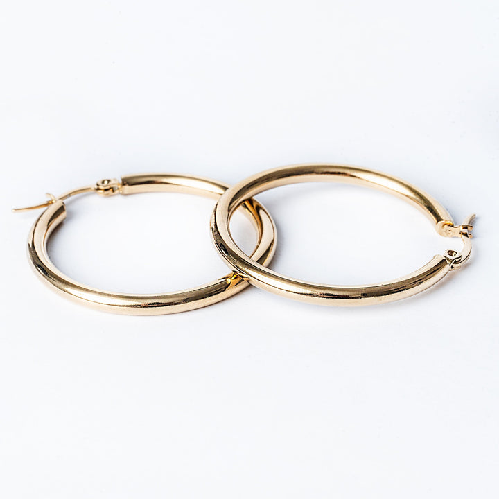 Stefania gold earrings standing in the center of the image against a white background. 