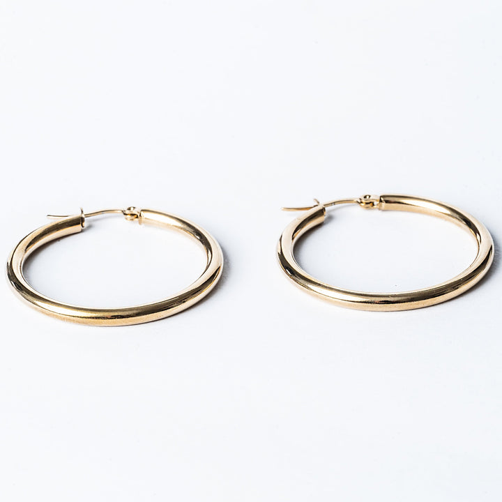 A pair of yellow gold Stefania hoop earrings on a white background