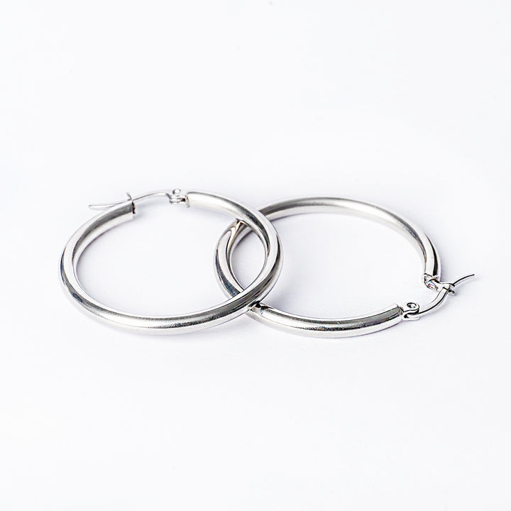 A close up view of stefania silver earrings standing in the center of he image on top of each other against a white background. 
