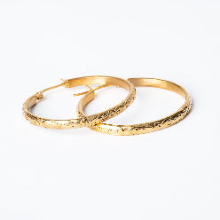 A pair of Sue Hoop Earrings with a textured surface, displayed against a white background.