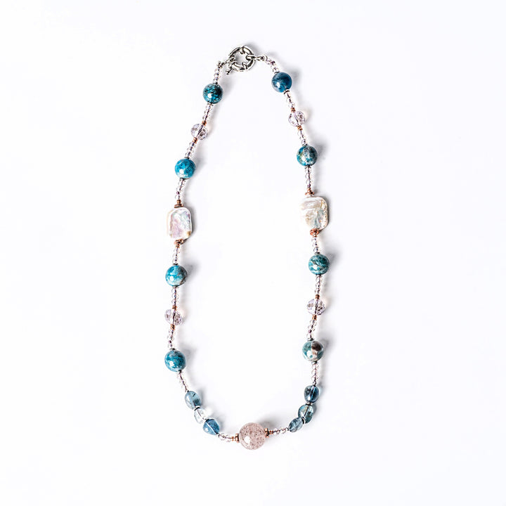 A bird view of Teal Necklace standing in the center of the image against a white background 