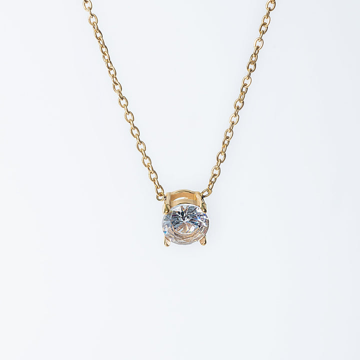 Gold Tessa necklace with a single round clear gemstone pendant shown from the front.