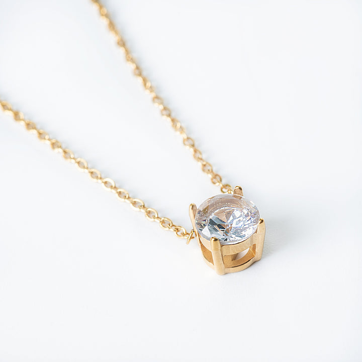 Gold Tessa necklace featuring a single round clear gemstone pendant.