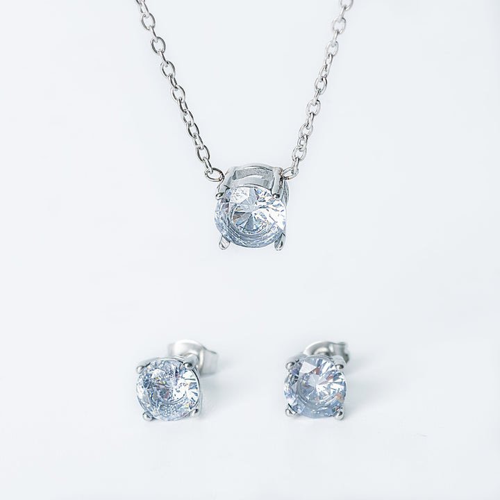 Silver Tessa jewelry set featuring a necklace with a single clear gemstone pendant and matching stud earrings.