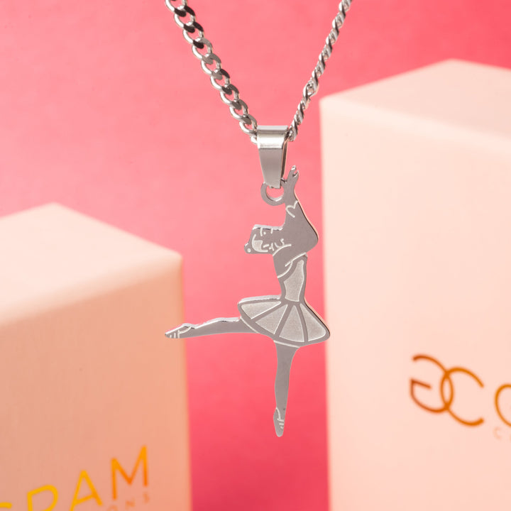 The Ballerina Necklace standing in the center of the image in front of its two uniquely designed boxes surrounded by a red background. 