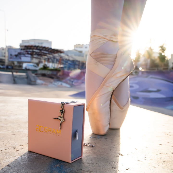 Ballerina dancing outside in front of gram collections ballerina necklace box. 