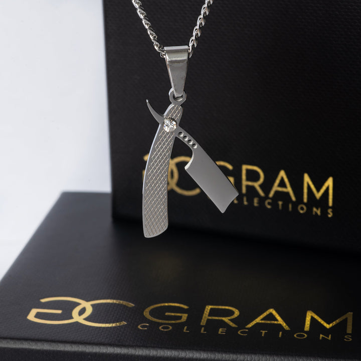 A close up view of barber necklace standing in front of its two uniquely designed boxes. 