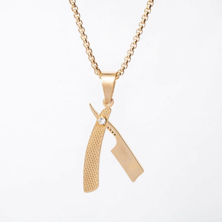 A gold-colored stainless steel Barber necklace with a pendant shaped like a straight razor.
