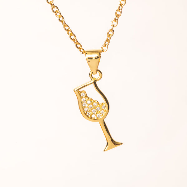 A gold-plated stainless steel Bartender necklace with a pendant in the shape of a glass with a diamond-like pattern on the stem, attached to a gold-plated chain.