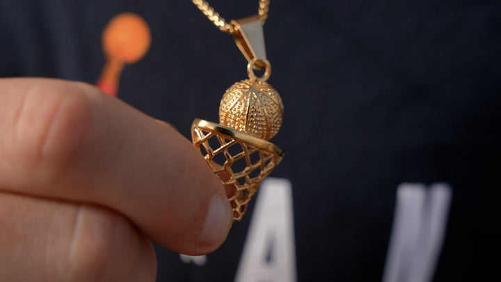 Model wearing The Basketball Player Necklace arround his neck, while holding its pendant in his hands. 