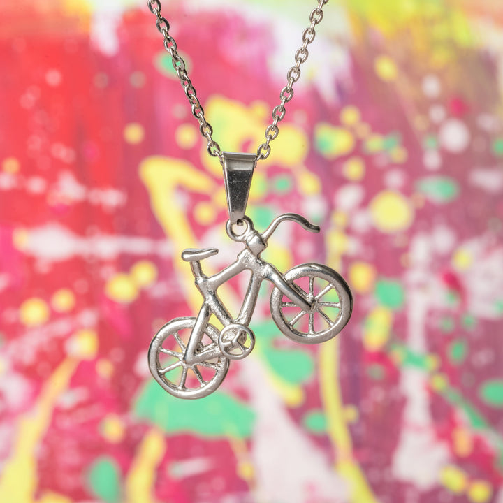 The biker pendant attached to its chain standing in the center of the image againsta colorful background in red, pink, yellow, and green colour. 