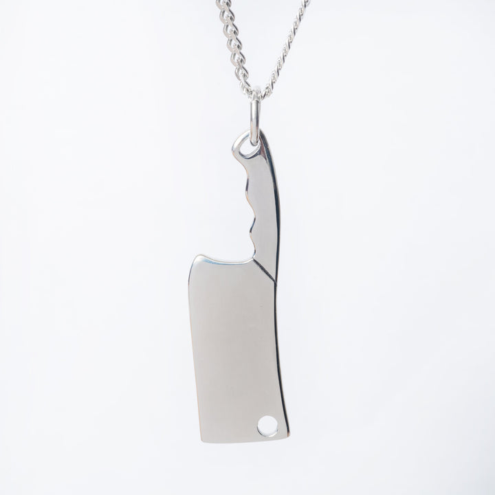 A close up view of silver colour chef necklace stnading in the center of the image against a white background. 