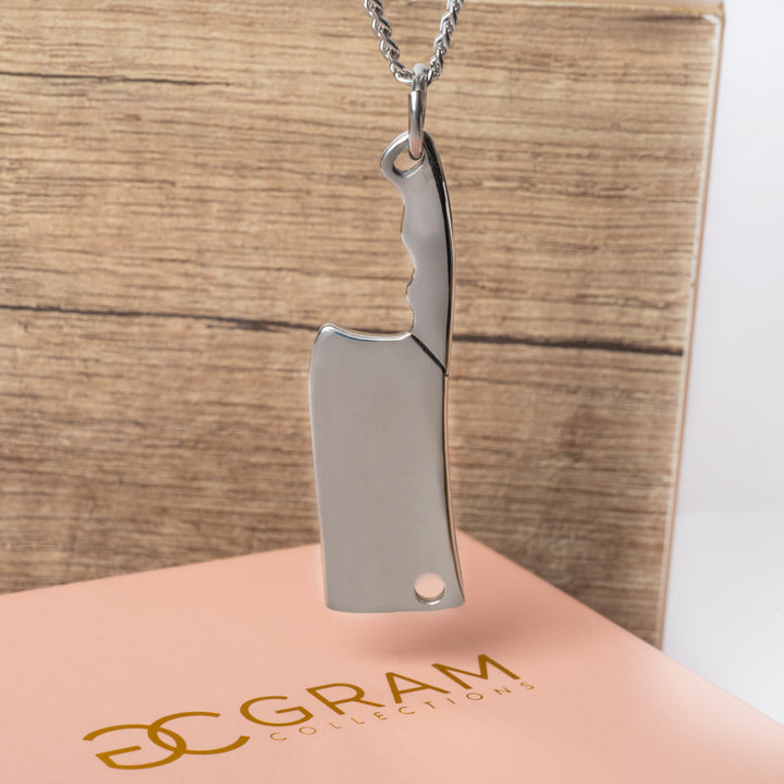 The Chef Necklace standing in the center of the image on top of its pink colour box. 