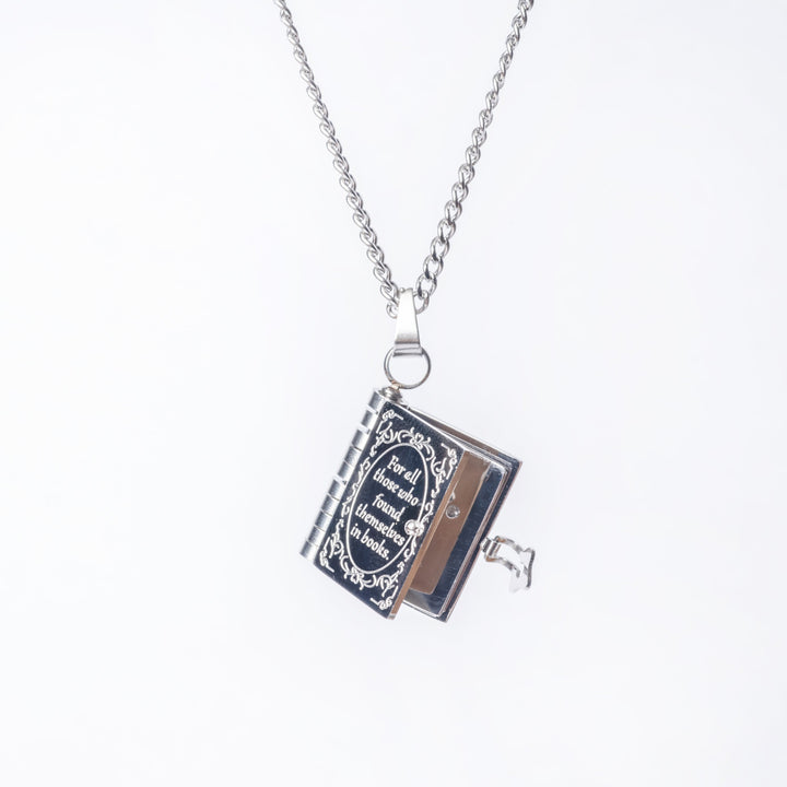 A close up view of educational necklace standing in the center of the image against a white background, attached to its chain. 