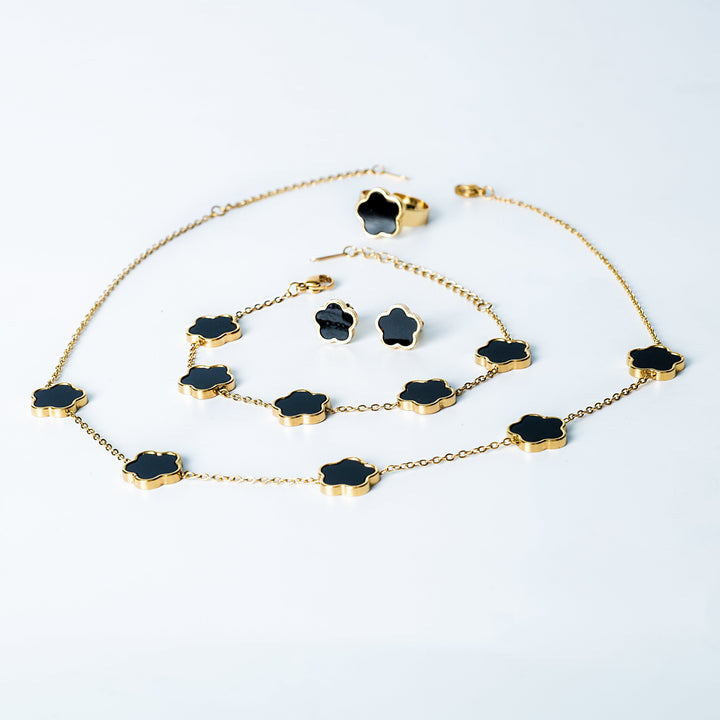 Fiore Set in gold featuring a matching black flower necklace, bracelet, earrings, and ring displayed on a white background