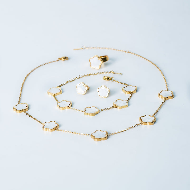 Fiore Set in gold featuring a matching white mother-of-pearl flower necklace, bracelet, earrings, and ring displayed on a white background