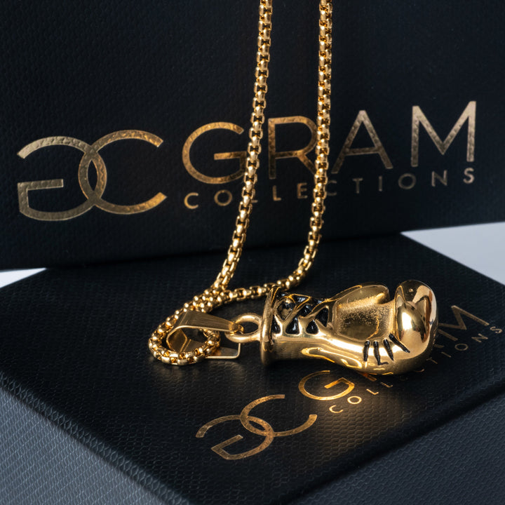 The gold colour Boxer Necklace placed on its uniquely designed box. 