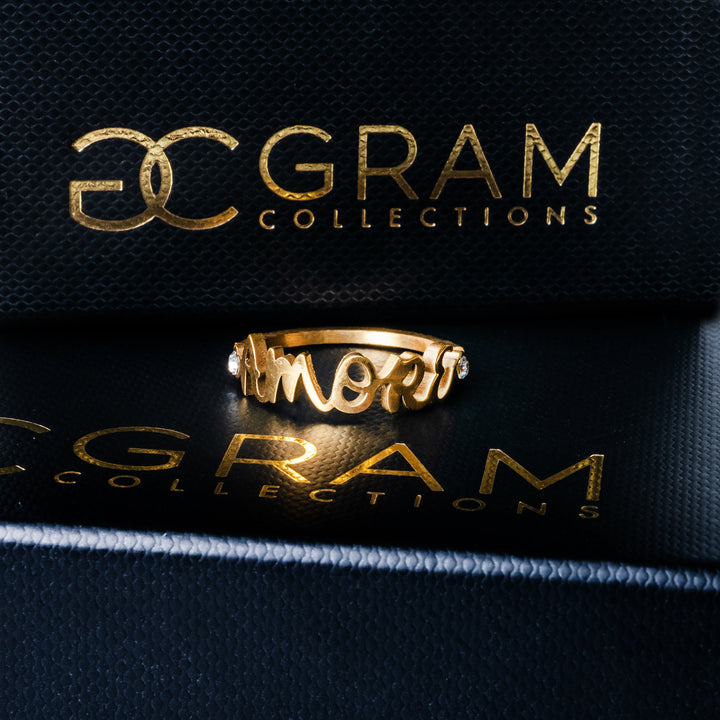 The gram collections gold plated amore ring placed on its black box. 