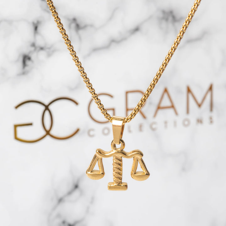 A close up view of The Lawyer Necklace standing in front of its uniquely designed white box. 