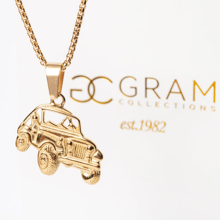 A gold-colored stainless steel  Off Road Necklace with a pendant in the shape of a car. The chain is displayed in the background with the brand 'G Gram Collections' featured.