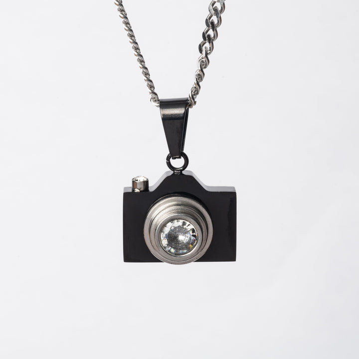 A close up view of The Photographer Necklace in black colour, standing in the center of the image against a white background. 