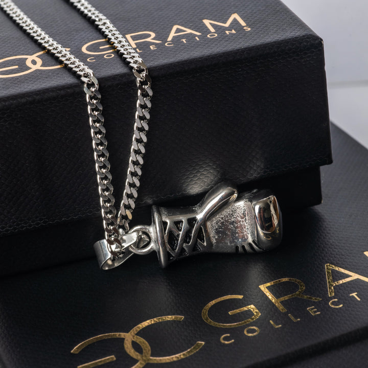 The silver colour Boxer Necklace placed on its uniquely designed box. 