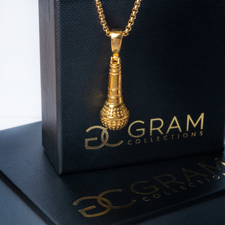 The singer necklace attached to its uniquely designed gram collections black colour box, that stands on top of another black box, surrounded by a white background.