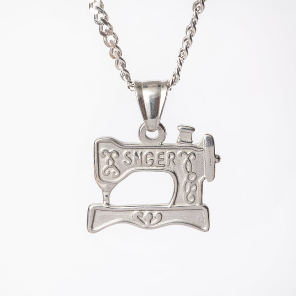 A silver stainless steel necklace with a pendant in the shape of a sewing machine.