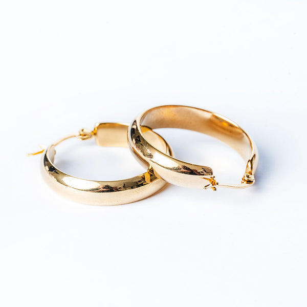 A pair of yellow gold stainless steel hoop Ritianne Earrings with a textured surface, displayed against a white background.