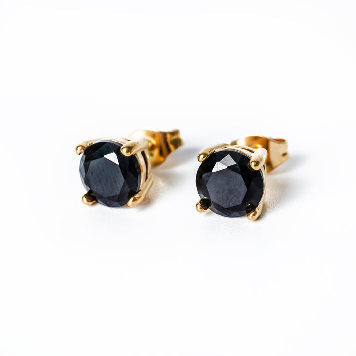 A close up view of Tommy Black Earrings standing against a white background 