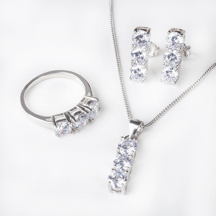 A close up view of Trilogy Earrings close up view, consist of ring end necklace, placed all over the image, standing against a white background. 