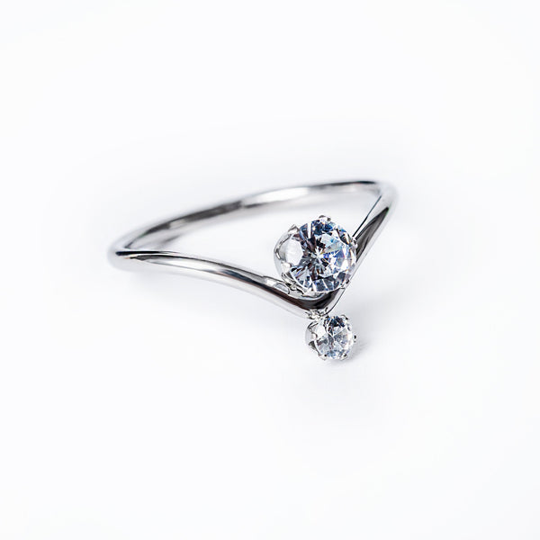 A silver-colored stainless steel ring with a single central cubic zirconia gemstone, set in a classic six-prong setting, surrounded by smaller clear crystals.