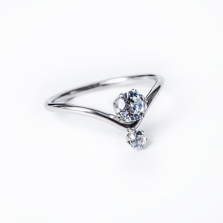 A silver-colored stainless steel ring with a single central cubic zirconia gemstone, set in a classic six-prong setting, surrounded by smaller clear crystals.