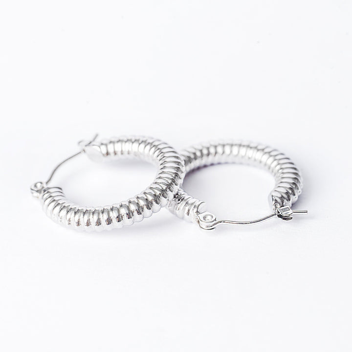 A close up view of Vivi Silver Earrings standing on top of each other against a white background. 