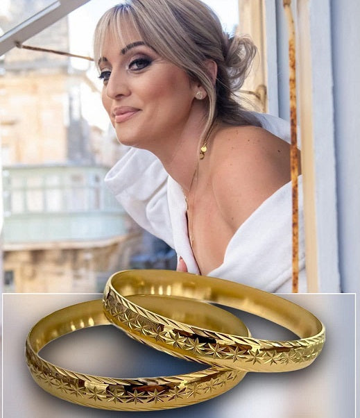 A woman wearing a white top and looking out from a window, with a gold-colored ring on her finger.