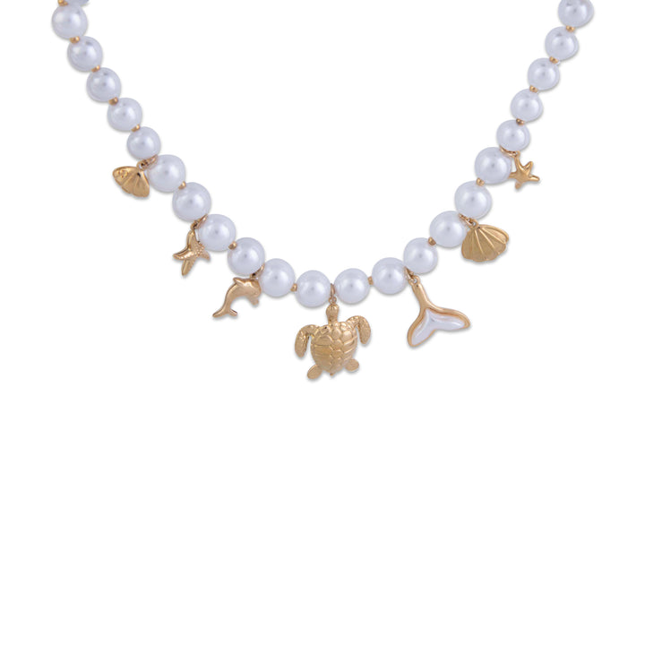Necklace with pearl beads and gold charms on a white background, zoomed. 