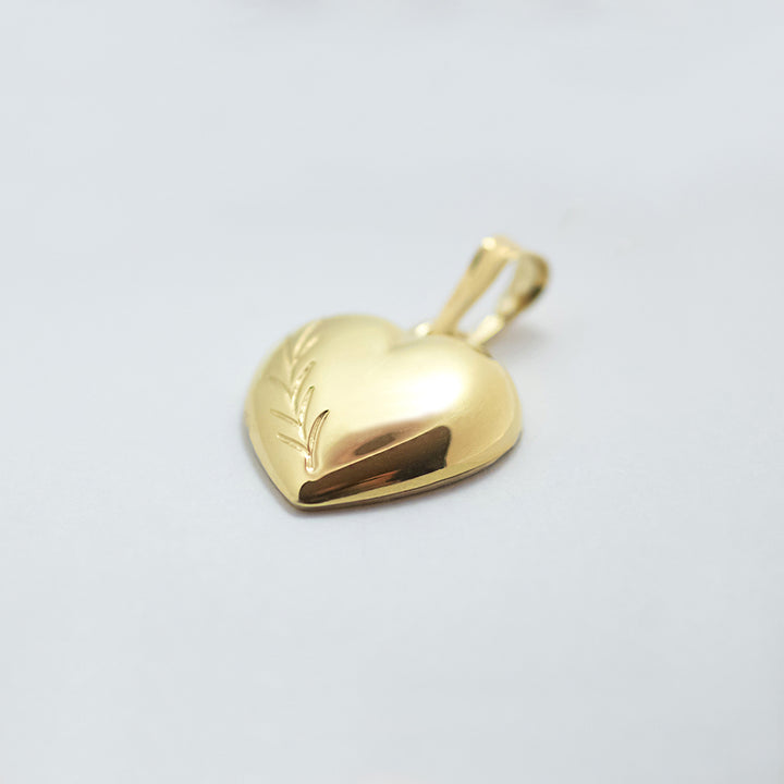 A close up view of Bliss Heart Gold Pendant standing in the center of the image, turn slightly on its left side. 