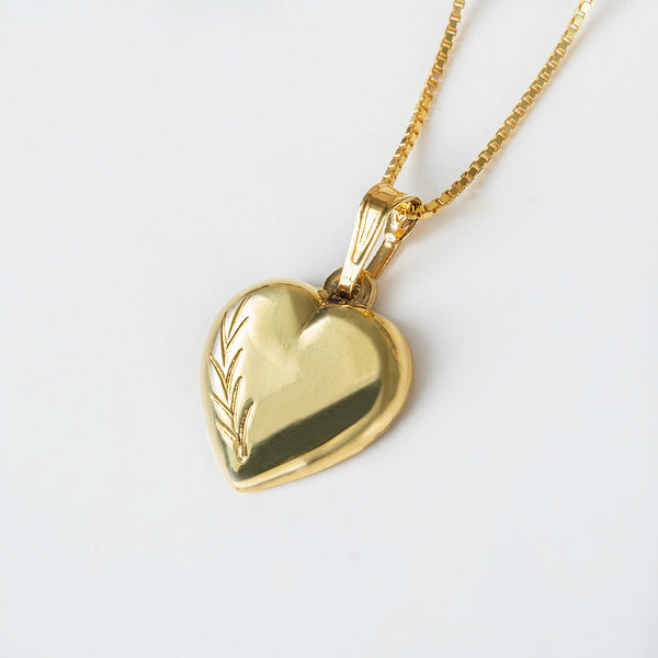 A gold-plated heart-shaped pendant on a chain against a white background