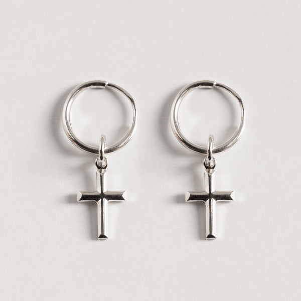 A pair of sterling Cross Silver Huggies earrings with a cross design.