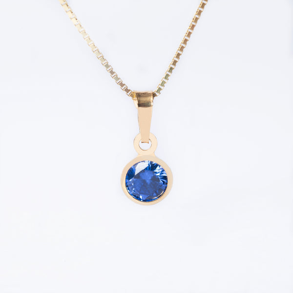 A yellow gold-plated sterling December Birth Stone pendant featuring a blue tanzanite cubic zirconia, attached to a gold-plated chain.