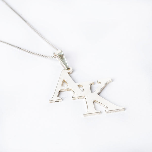 A sterling silver necklace with the initials 'A' and 'K' on a white background.