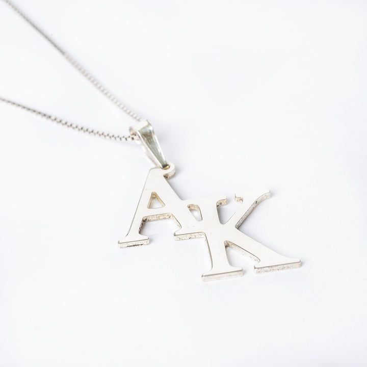 A sterling silver necklace with the initials 'A' and 'K' on a white background.