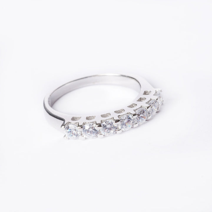 A silver ring with multiple cubic zirconia stones set in a row on a white background.