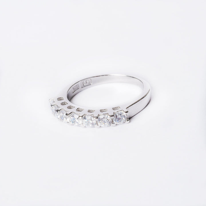 A silver ring with multiple cubic zirconia stones set in a row on a white background.