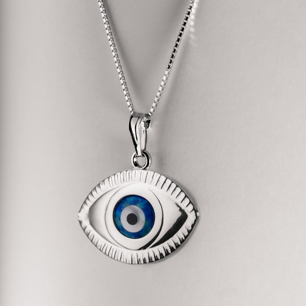 A silver pendant featuring a blue and white evil eye charm on a chain against a light background.