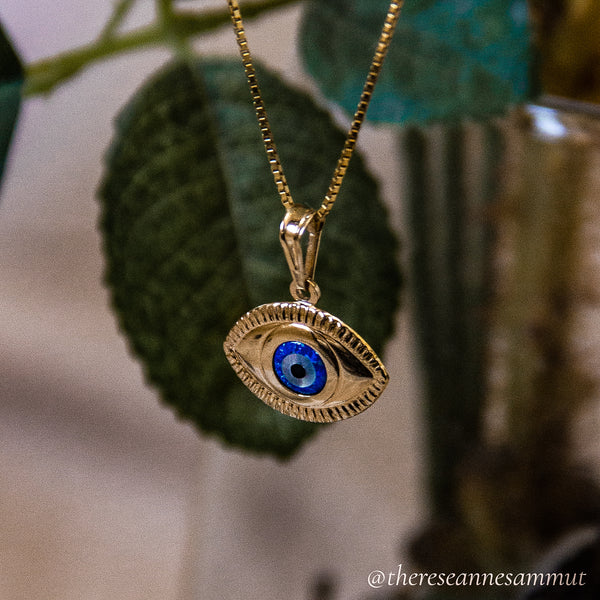 A gold-plated sterling silver pendant with a blue and yellow eye design, suspended from a chain.
