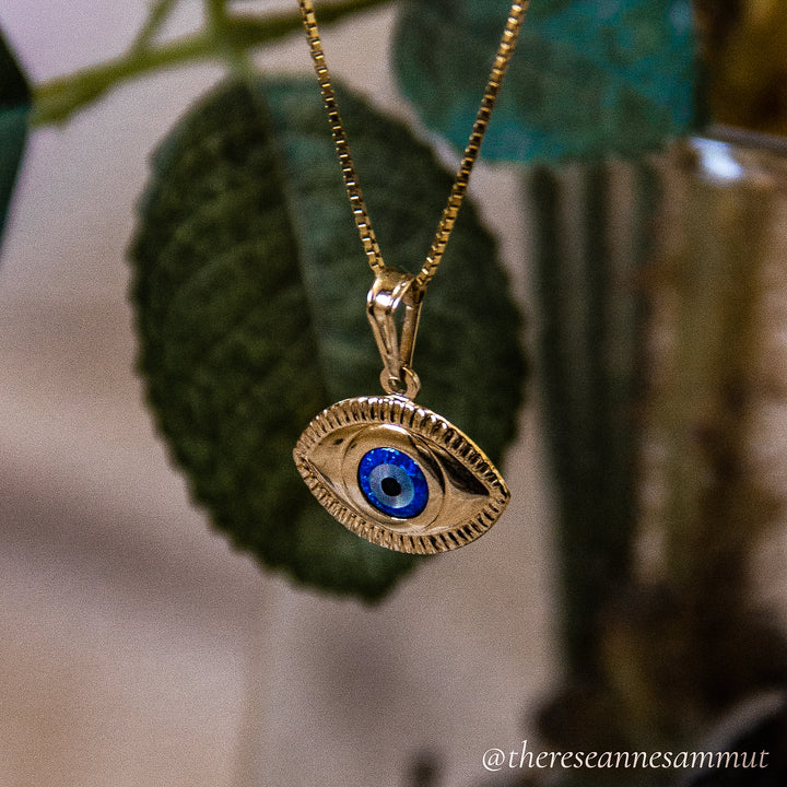 A gold-plated sterling silver pendant with a blue and yellow eye design, suspended from a chain.